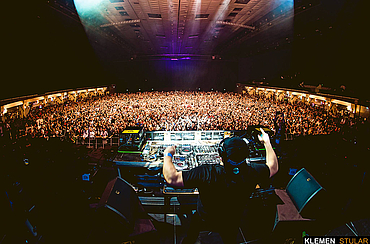 Konzert in der Wiener Stadthalle mit einem DJ der hinter seinem Pult vor einer feiernden Menge steht